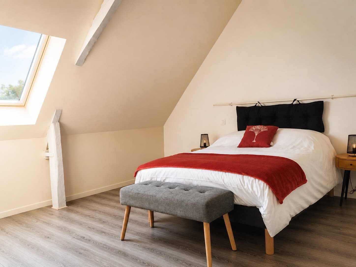 Chambre sous les combles avec poutres claires et touches rouges
