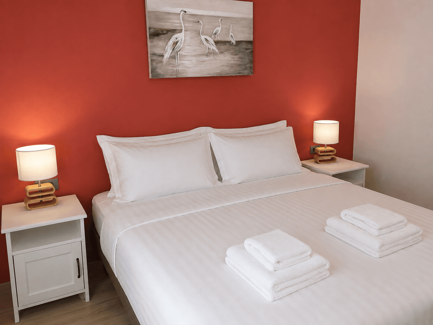 Chambre préparée avant une arrivée : lit fait, serviettes pliées, lampes de chevet allumées